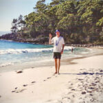 A skinnier Steve in his Scream t-shirt waves from the famous white sands